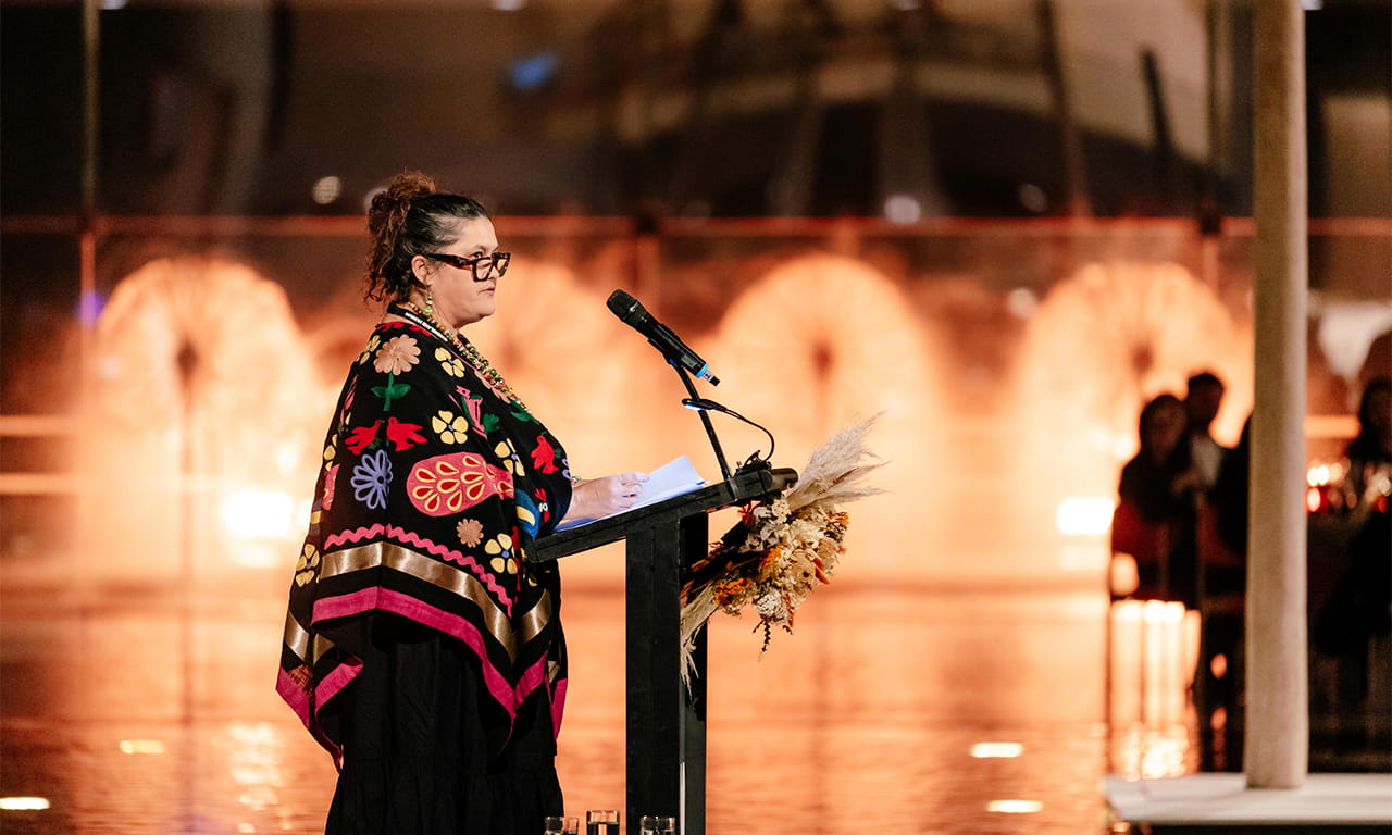 QAGOMA Board of Trustees and Indigenous Advisory Panel member Dr Bianca Beetson (Gubbi Gubbi/Kabi Kabi and Waradjuri peoples) addressing guests at the First Nations Bespoke Dinner during NAIDOC Week, QAG Watermall, July 2023 / Photograph: Chloë Callistemon.  
