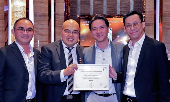 The project team celebrates their achievement, receiving the award on stage and capturing the moment together with pride.