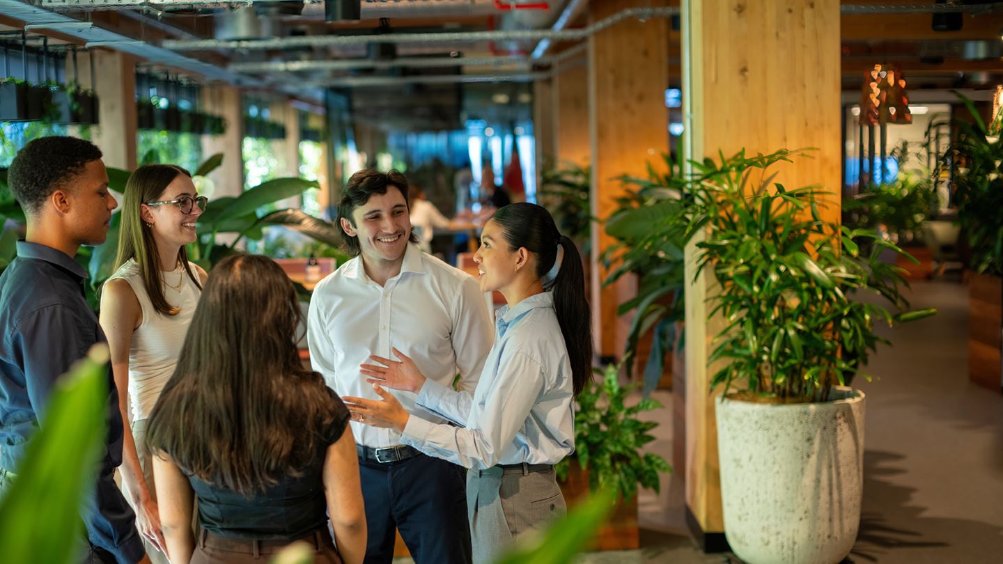 Aurecon graduate employees chatting in a modern green office.
