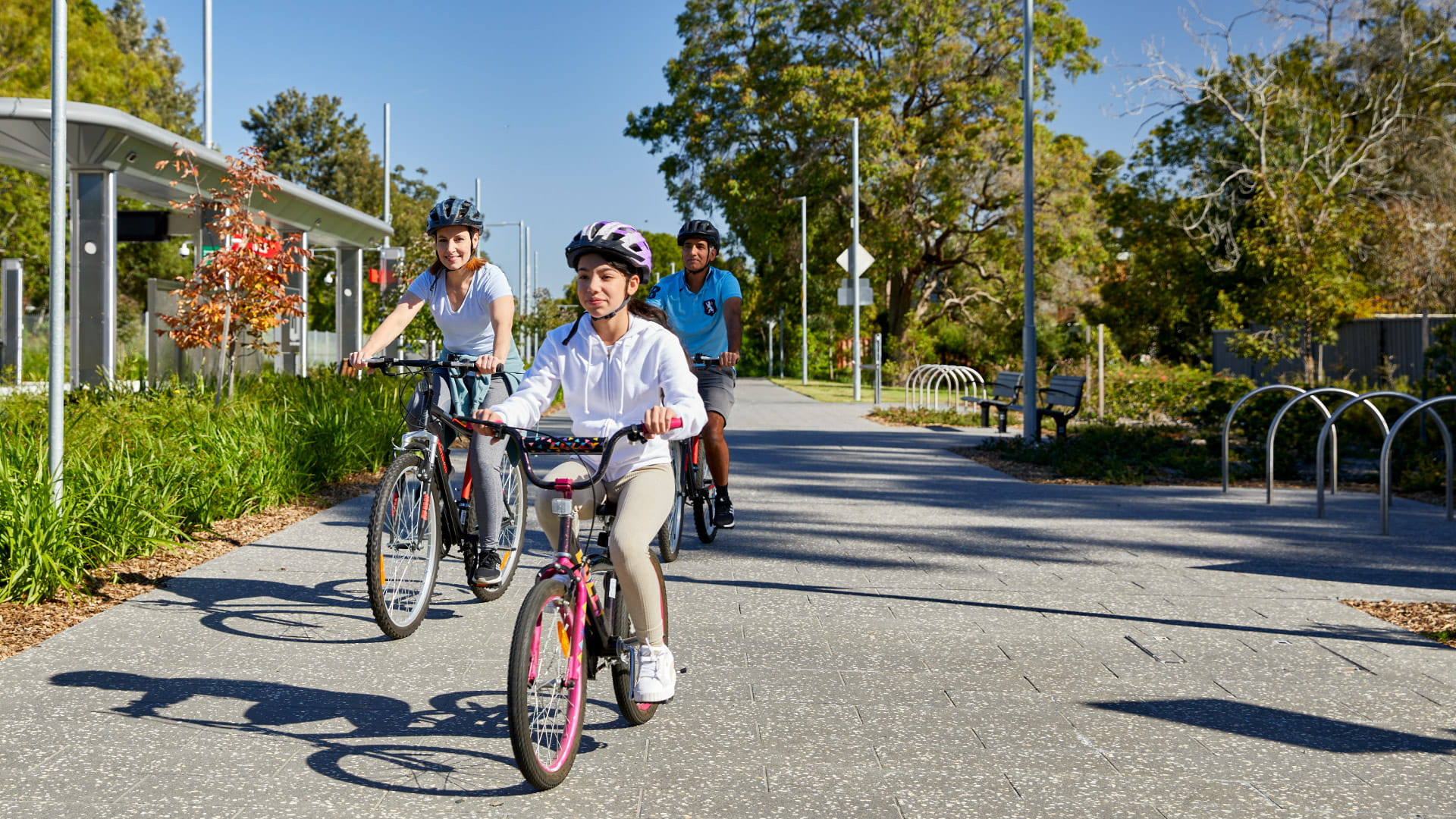Family cycling past light rail station in Parramatta, Sydney.