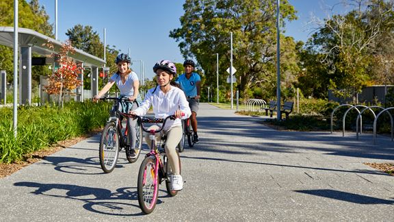 Family cycling past light rail station in Parramatta, Sydney.