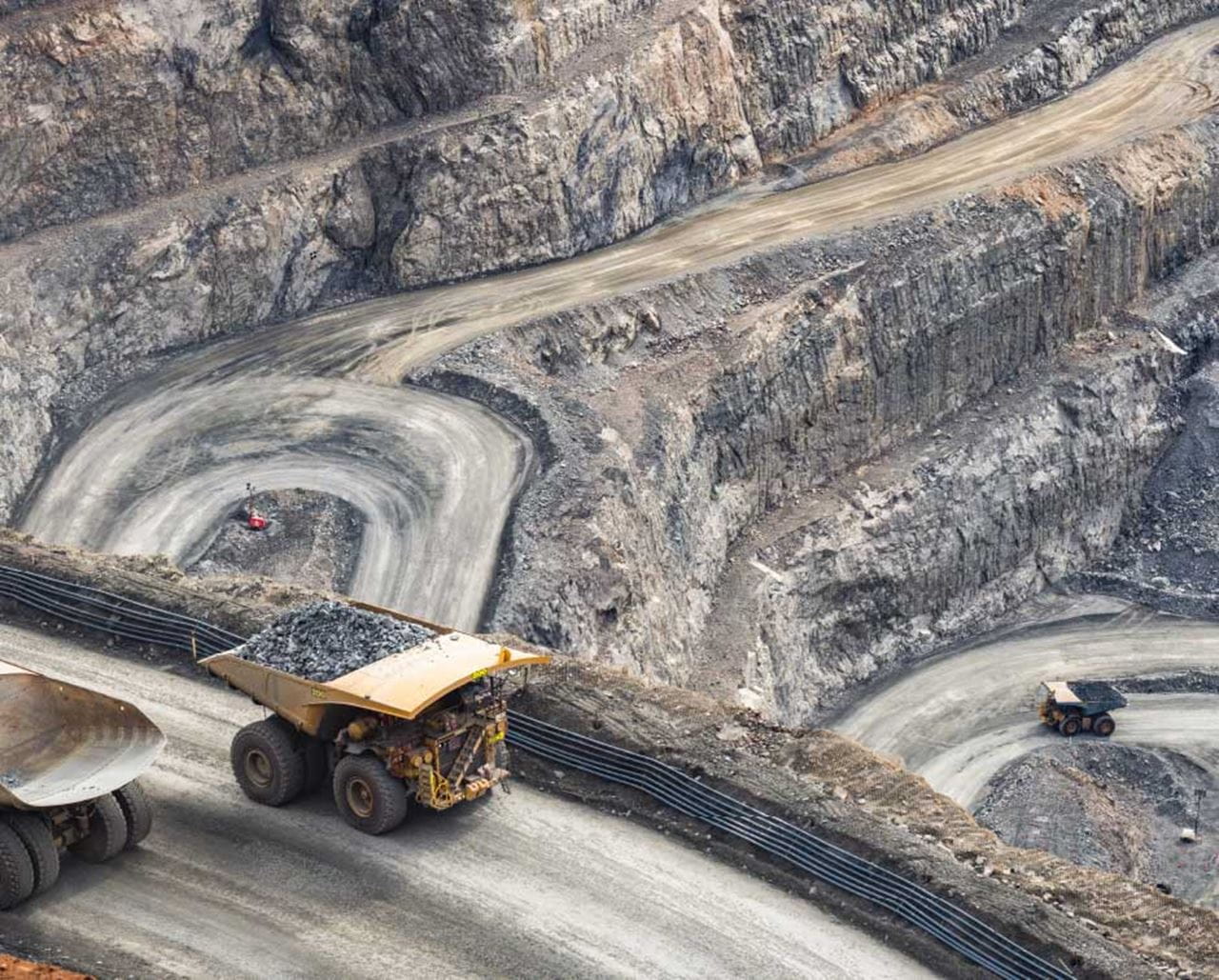 Heavy earth moving equipment transporting materials in quarry.