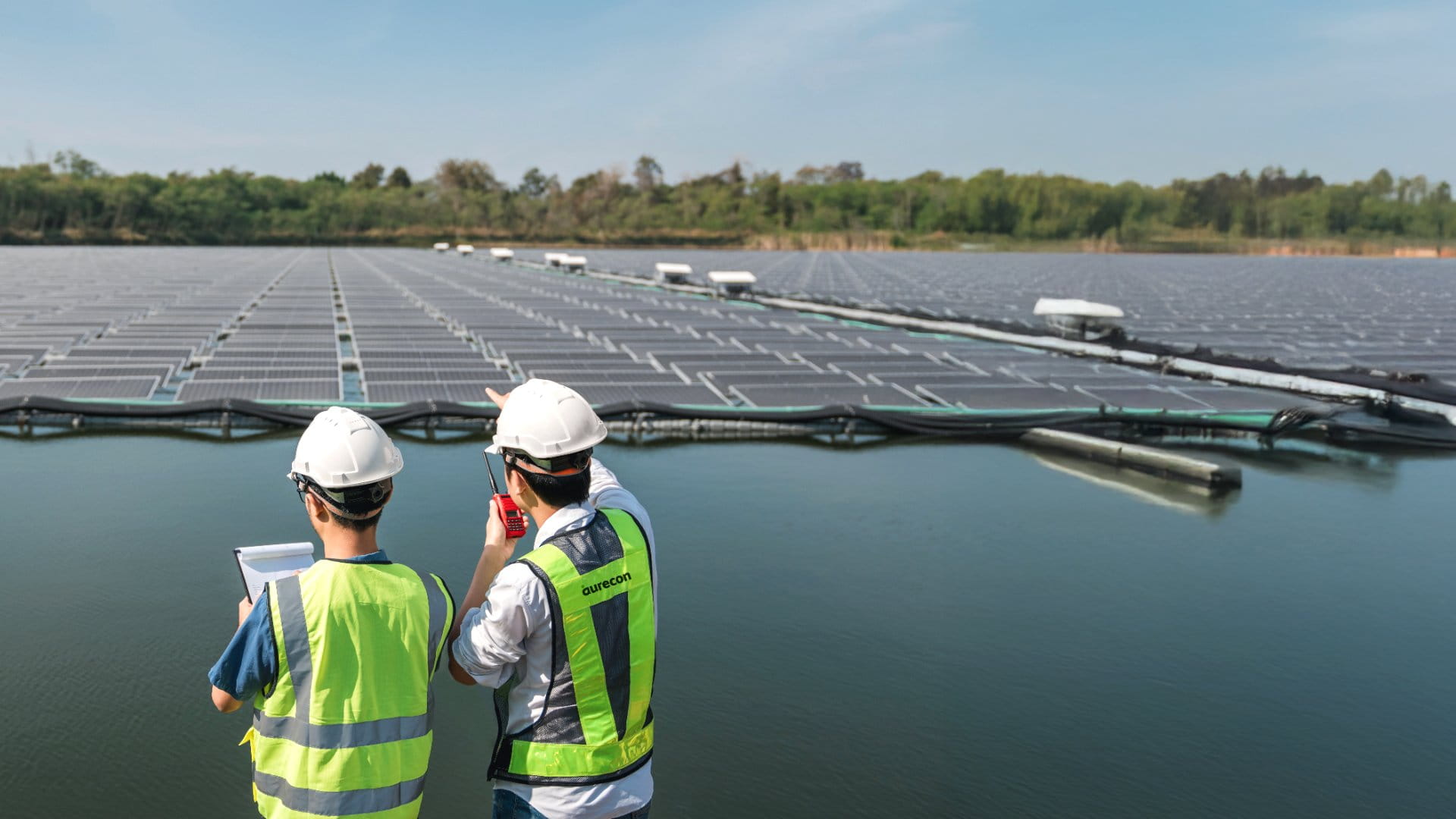 Two male workers inspecting floating solar farm in southeast Asia.