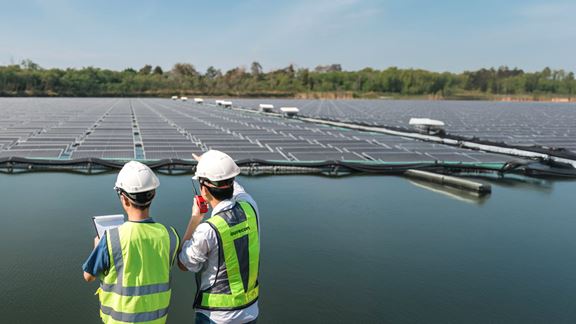 Two male workers inspecting floating solar farm in southeast Asia.