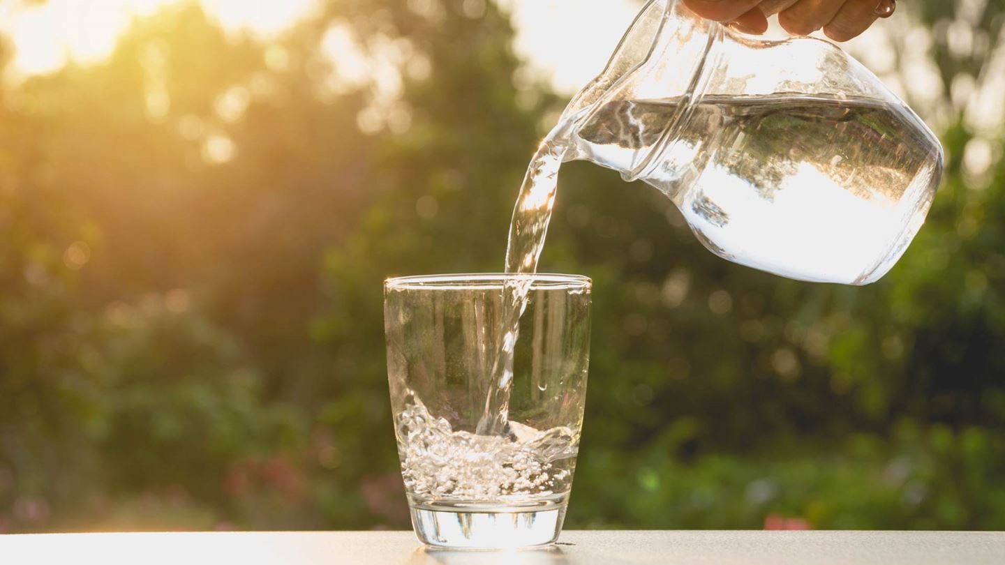 Woman pouring water from a glass jug into glass