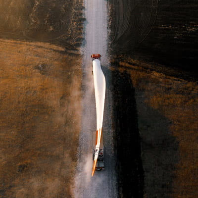 Wind turbine blade being transported by truck on a rural road.