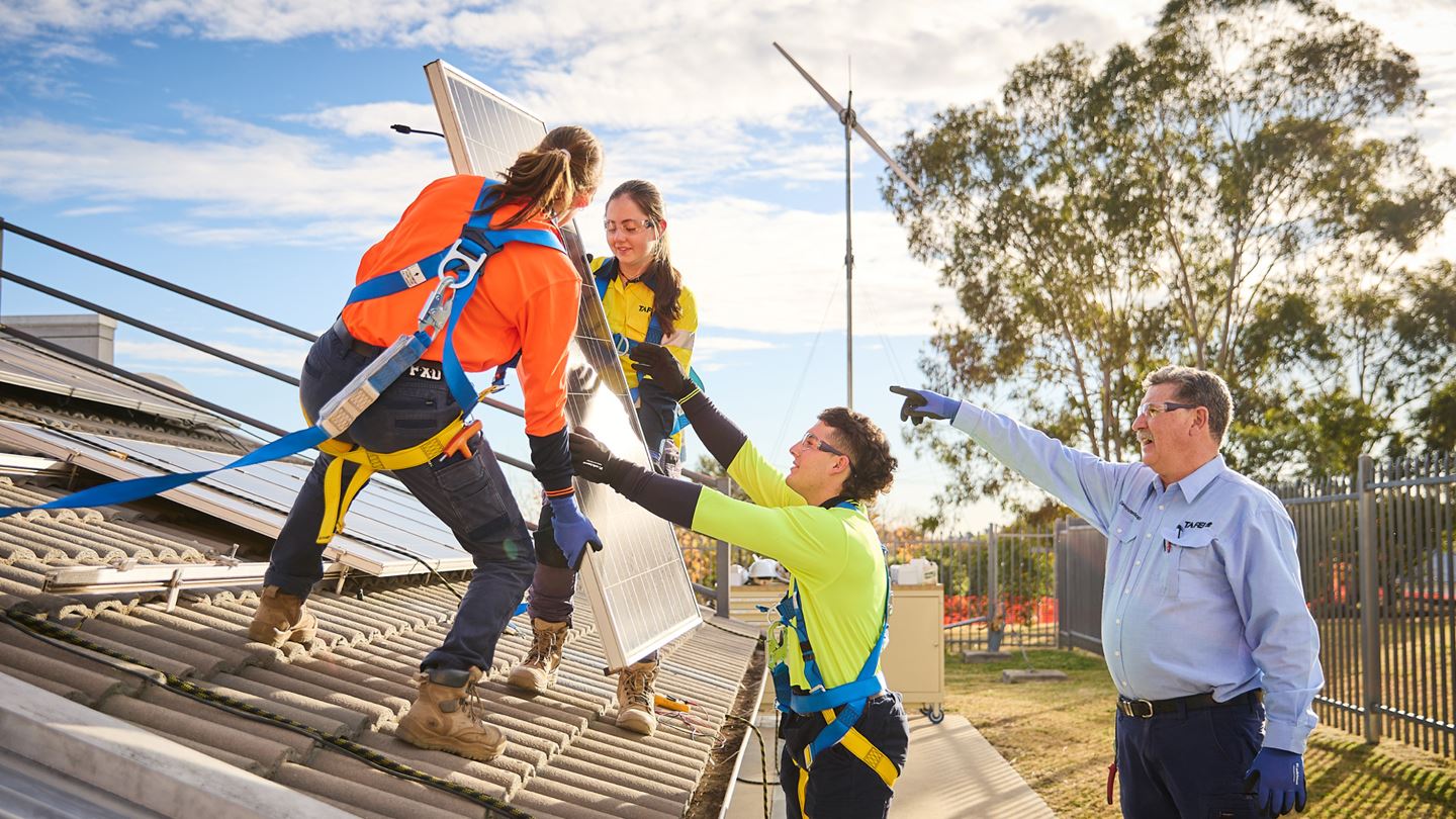 Students placing solar panels on roof with supervisor. Image courtesy of TAFE NSW.