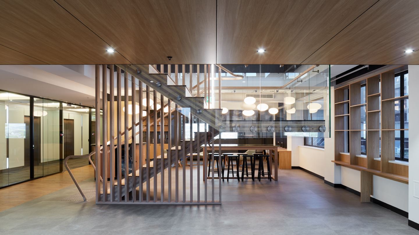 The staircase featured appears suspended from structural glass, providing the heart of connection across the three levels.