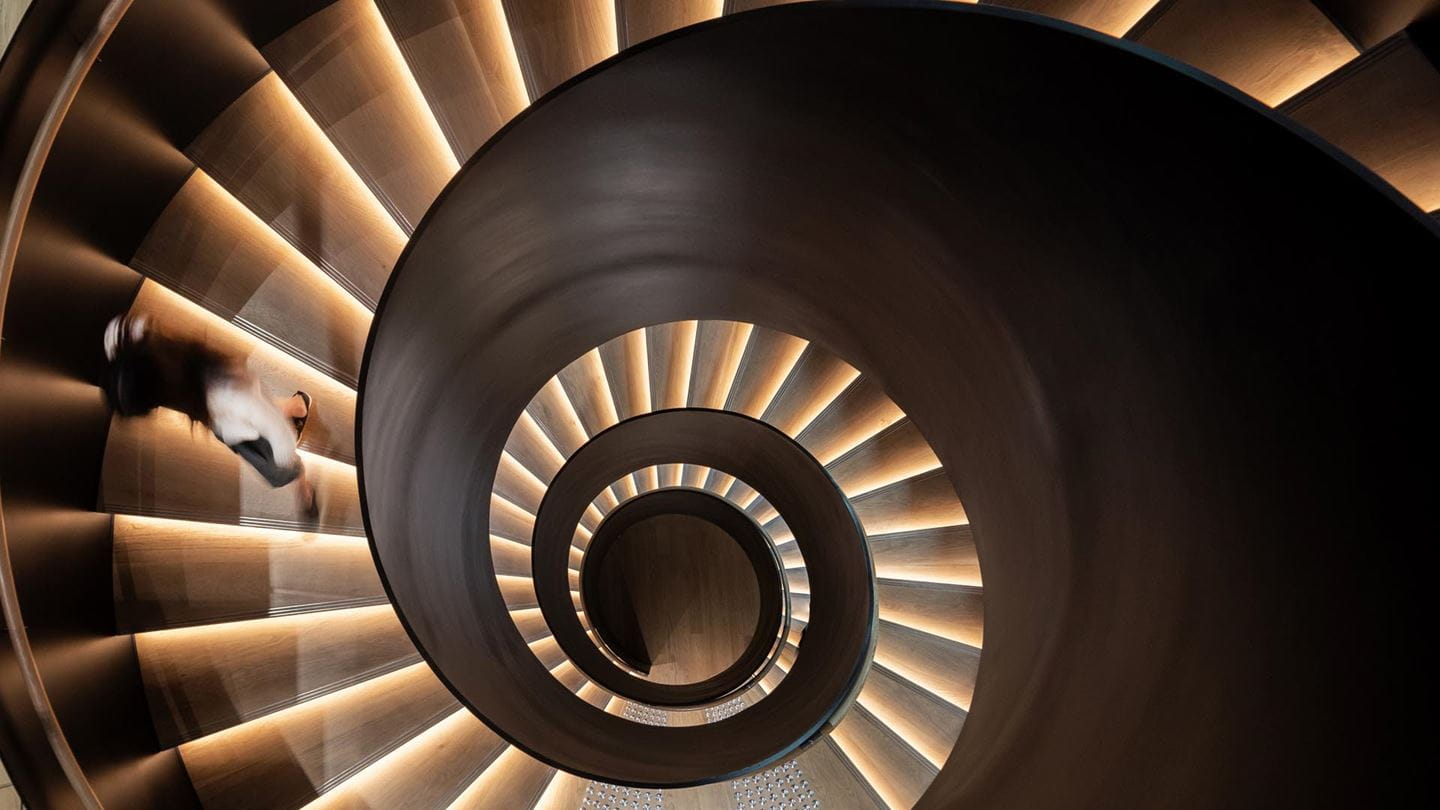 At the heart of Dyson's headquarters features a grand free-standing spiral staircase that boasts a sleek black exterior frame.
