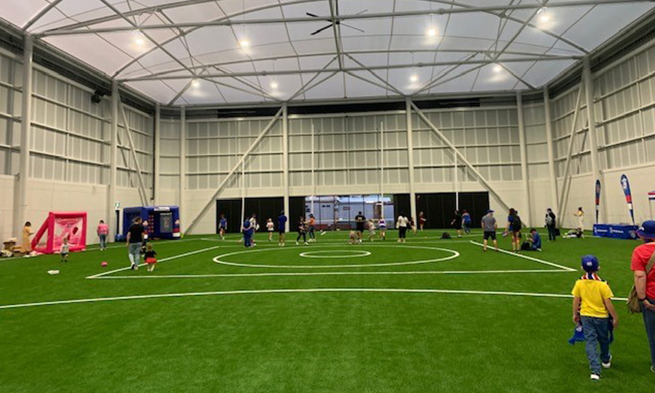 The development includes a large indoor training field with a stretched fabric roof, allowing teams and coaches to practice drills and set plays confidentially.