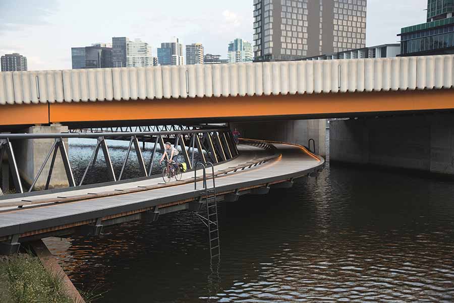 Cyclists on the Jim Stynes Bridge passing under the road bridge. Image courtesy of John Gollings.