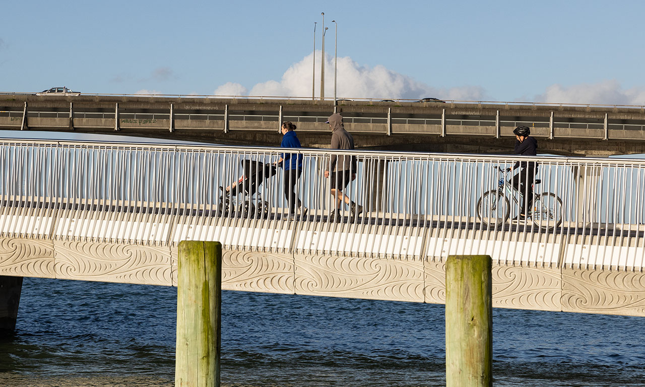 The concrete fascia panels along the bridge’s length feature a Puhoro design that symbolises movement through water, alternating with unahi, a pattern which relates to the scales of fish. Image courtesy of Mark Scowen Photography.