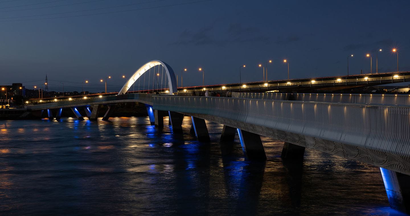 Feature lighting on the handrails, bridge piers and arch will ensure the Ngā Hau Māngere bridge is as visible by night as by day. Image courtesy of Mark Scowen Photography.